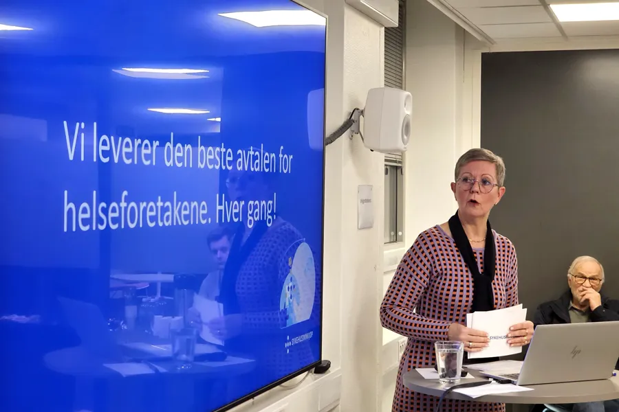 En kvinne som står ved siden av et bord med en bærbar datamaskin