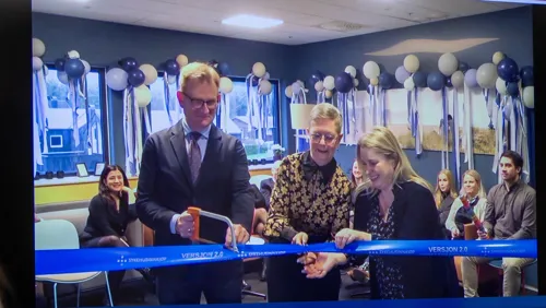 En gruppe mennesker står bak et banner som skal klippes. Ballonger i bakgrunnen.