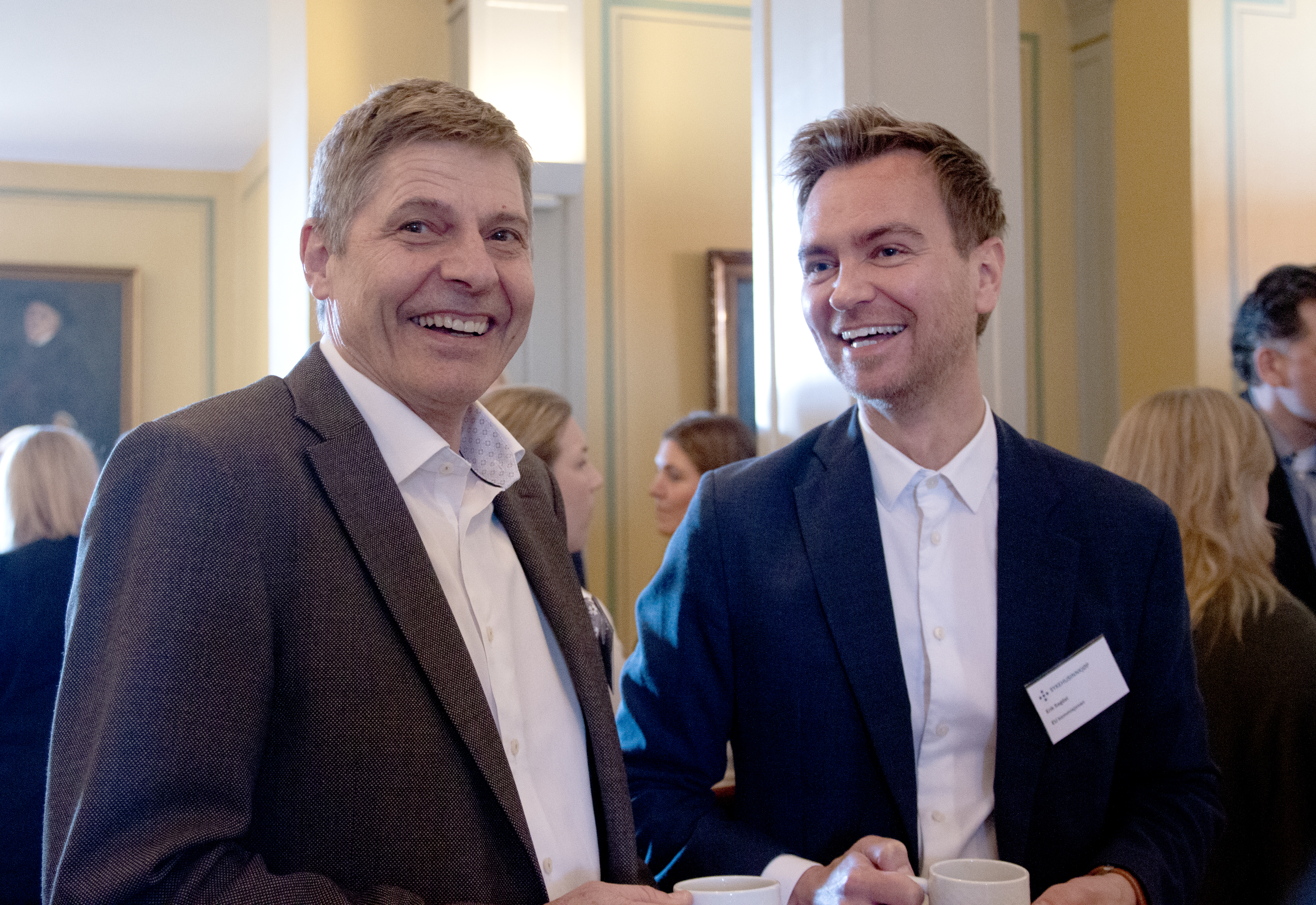 To menn snakker sammen og smiler.