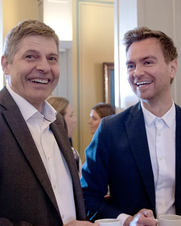 To menn snakker sammen og smiler.