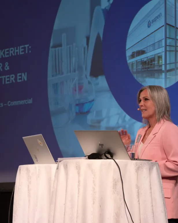 En dame står på en scene og snakker.