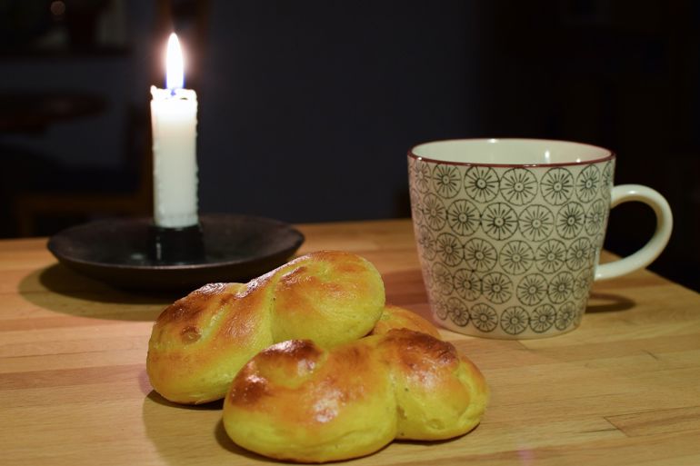 Stearinlys, kaffekopp og lussekatt.