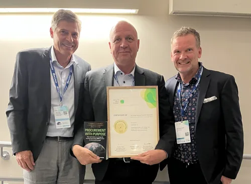 To representanter fra Sykehusinnkjøp og en fra danske Amgros står sammen og viser frem prisen.
