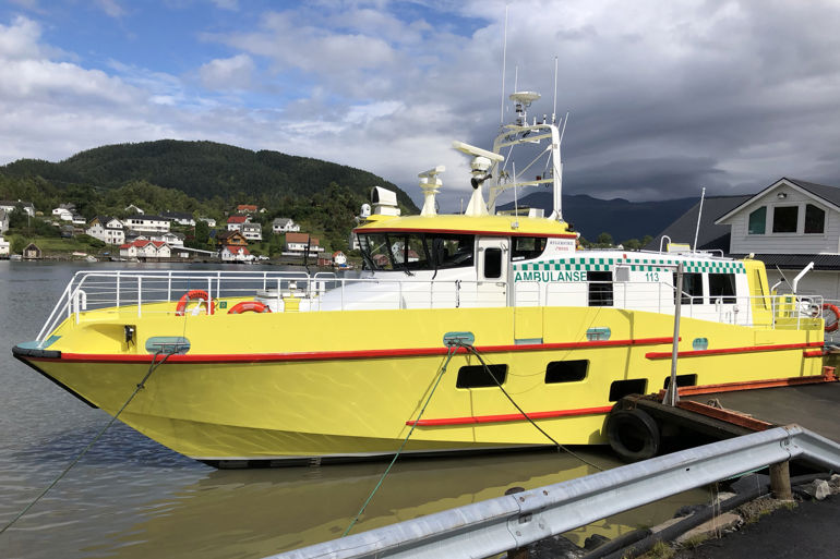 En gul ambulansebåt ligger på vannet. Båten skal settes i trafikk i Karlsøy kommune i Troms.