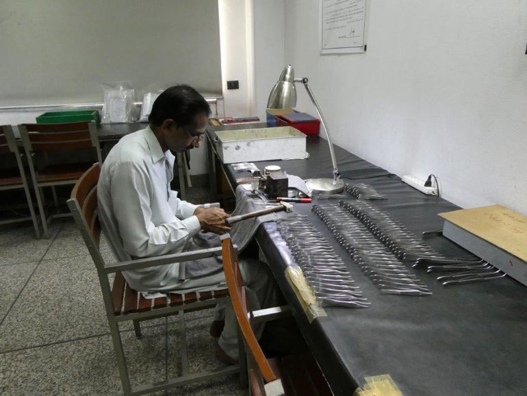 En mann arbeider med kirurgiinstrumenter.