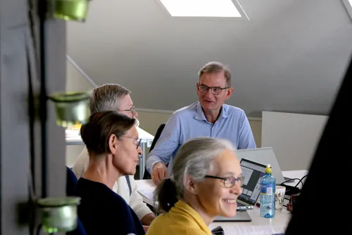 En smilende mann og tre kvinner sitter rundt et møtebord.