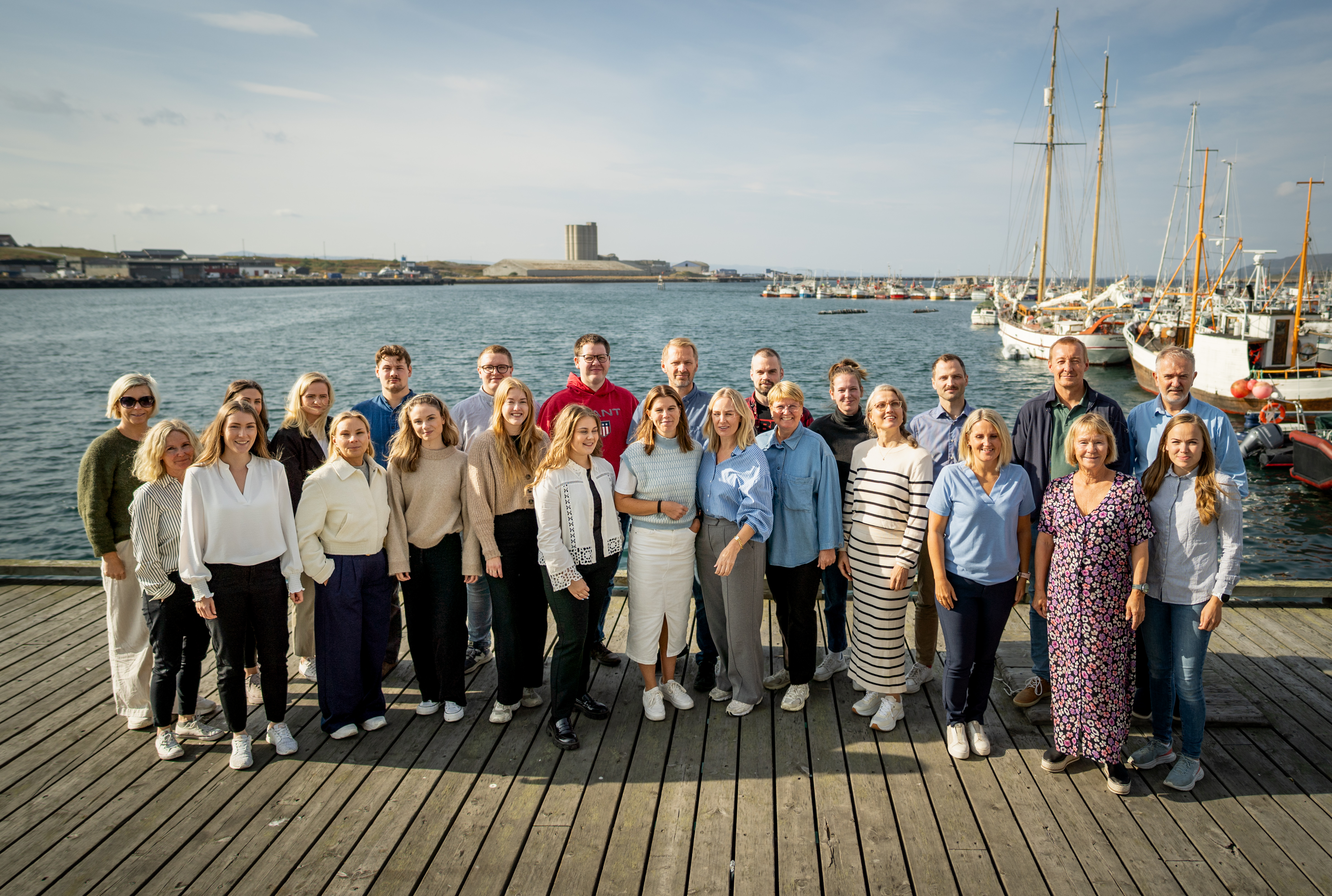 En gruppe mennesker står på en kai i solskinn