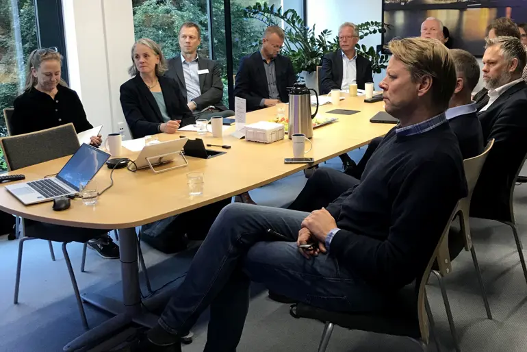 En gruppe mennesker som sitter rundt et bord med bærbare datamaskiner