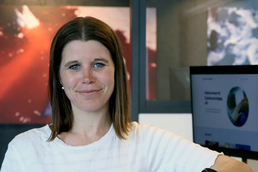 En smilende kvinne foran en pc-skjerm.