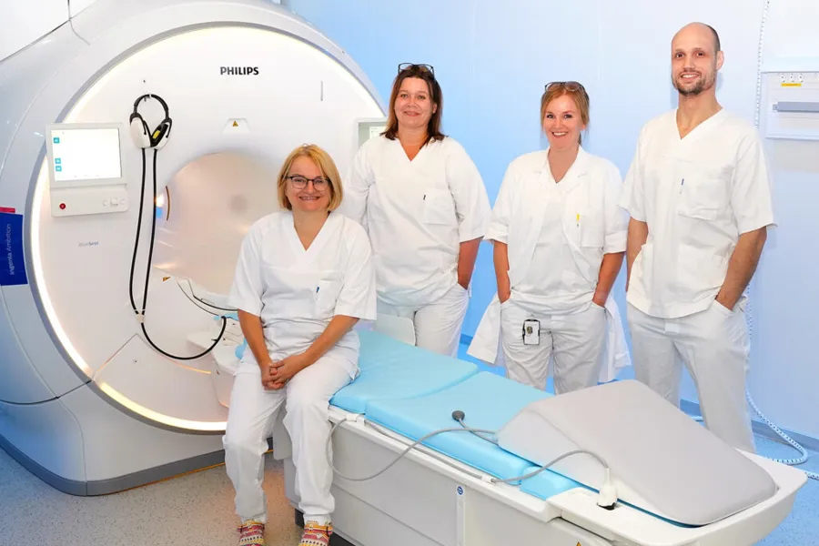 En gruppe mennesker i hvite laboratoriefrakker som står ved siden av en medisinsk maskin